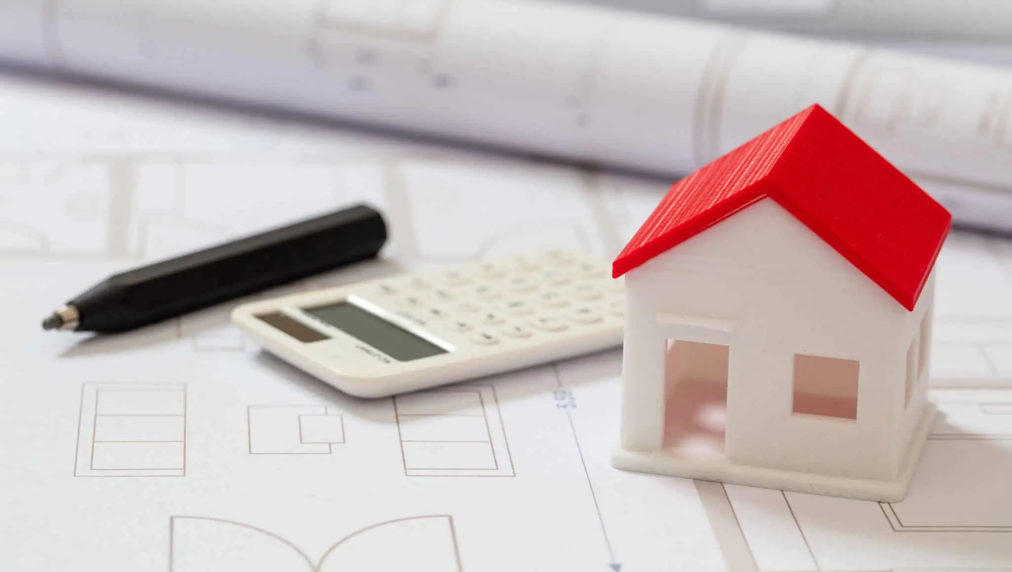 Calculadora e uma casa em cima da mesa a ilustrar os casos em que pode existir a Isenção e descontos no IMI em 2020