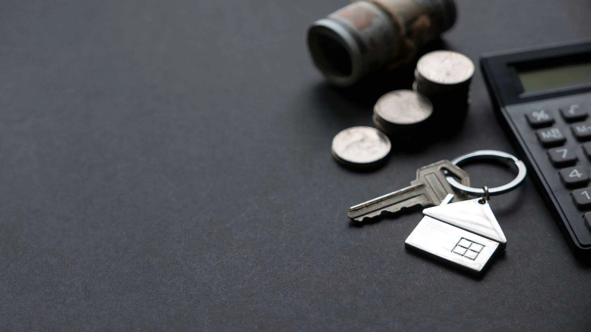 porta-chave com formato de uma casa. Ao seu lado uma pilha de moedas de euro