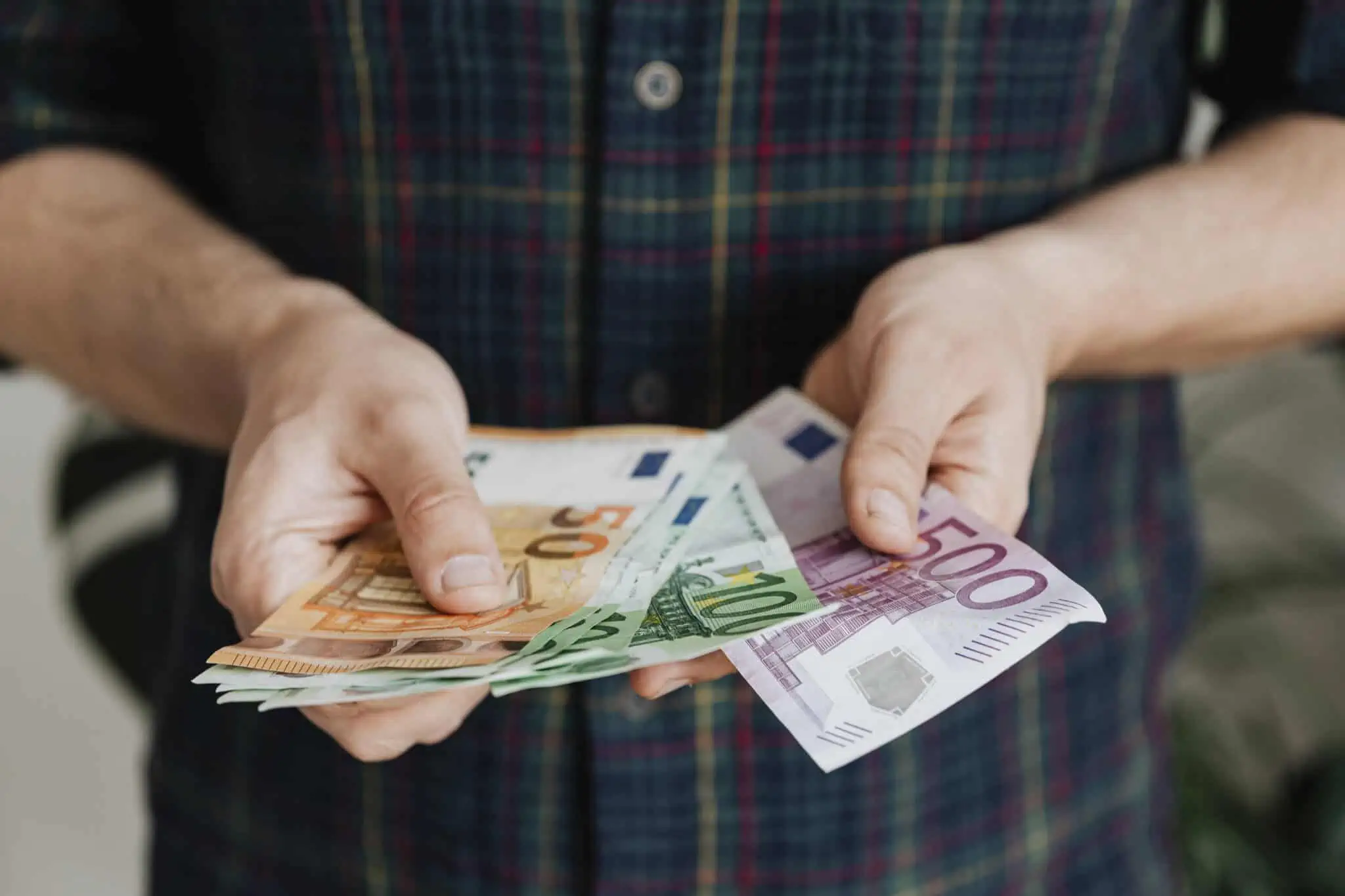 Prestações sociais: O que vai mudar em 2024? homem a contar notas a ilustrar o aumento das prestações sociais em 2024