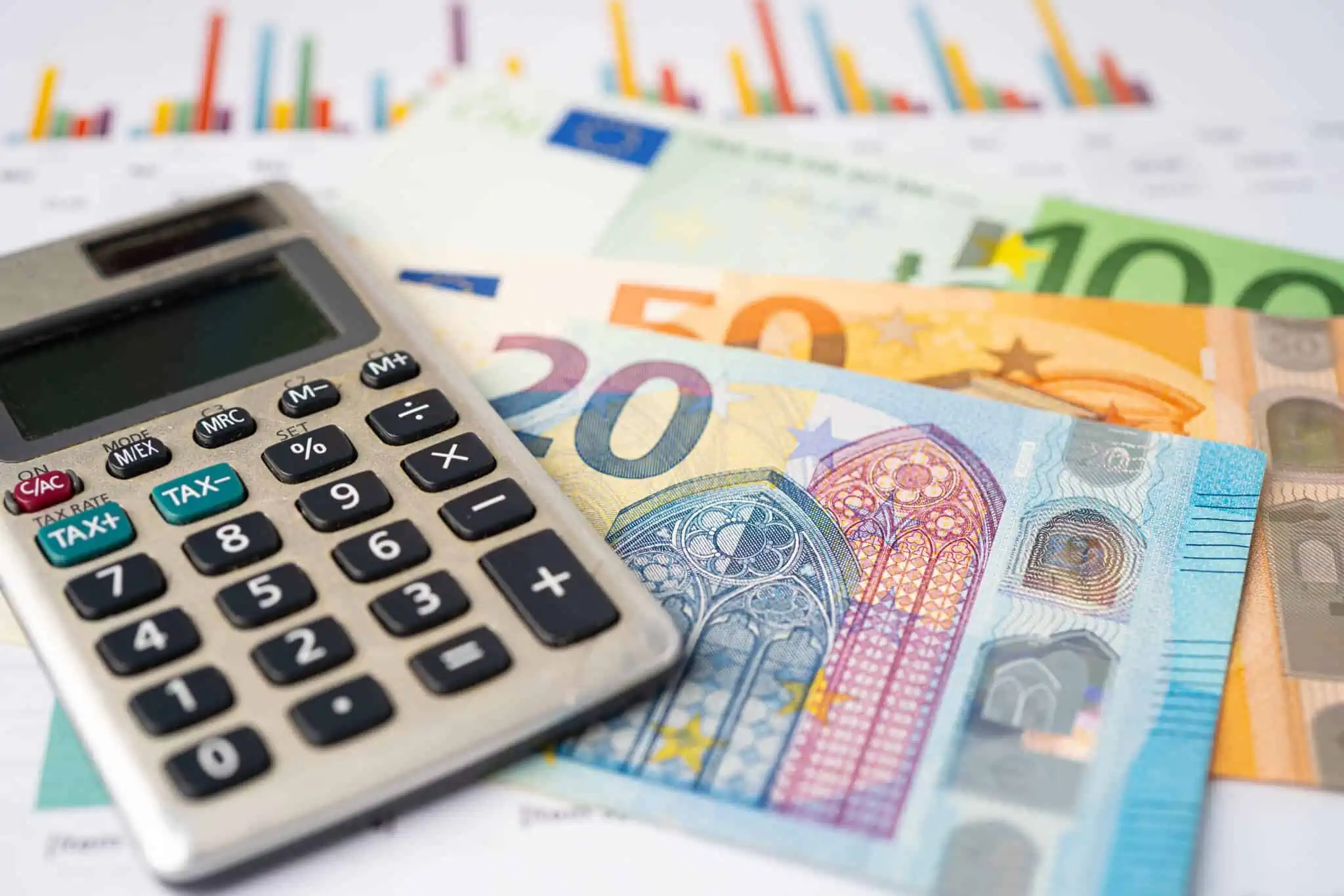 os termos financeiros BIC SWIFT e IBAN ilustradios por uma produção fotográfiica que mostra um molho de notas Euro, de diferentes valores e cores, junto a uma calculadora e documentos com gráficos