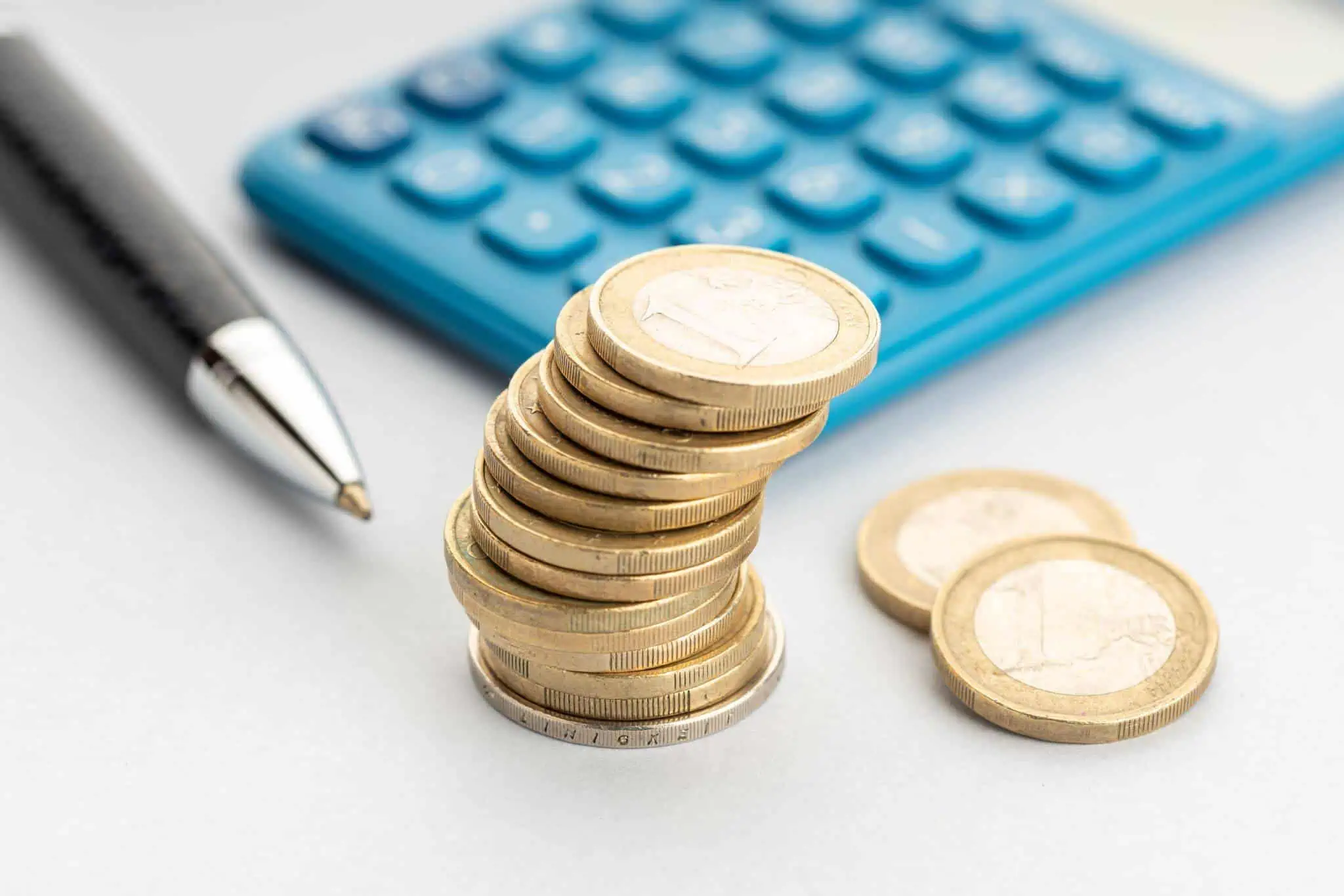 Como aumentar o reembolso de IRS até ao final do ano? caneta, moedas de euro e calculadora azul