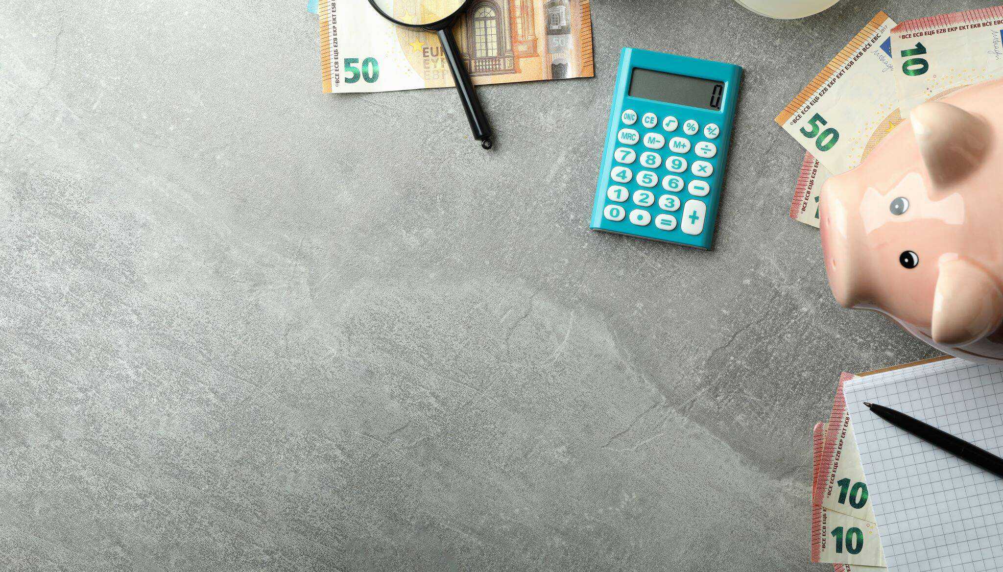 Porquinho mealheiro, calculadora e notas de 10, 20 e 50 euros em cima da mesa