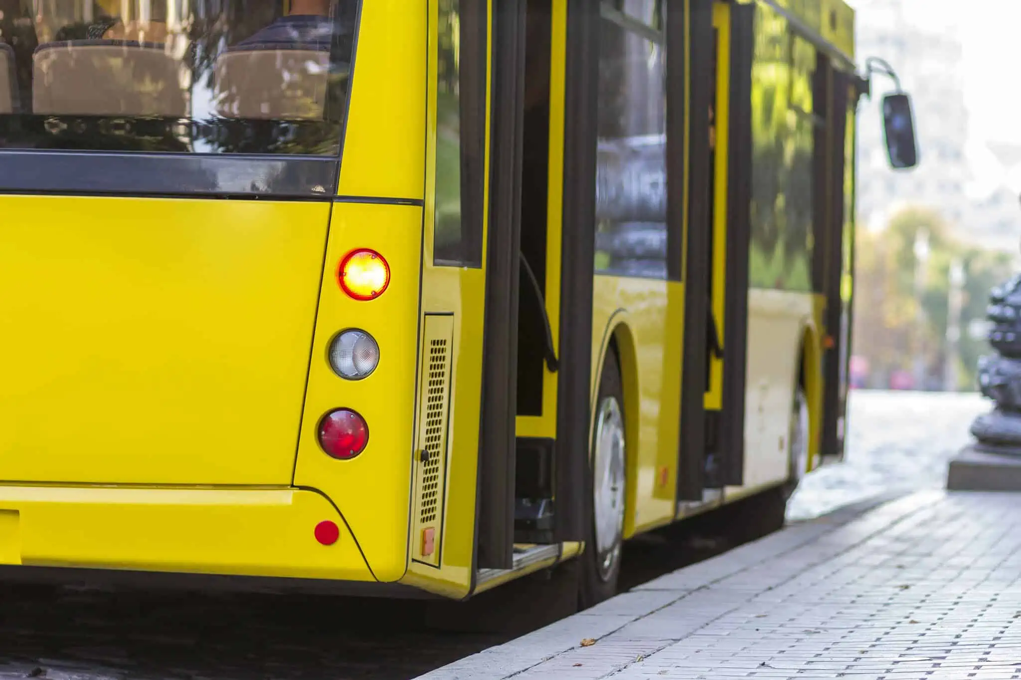 Transportes públicos: O que muda em 2024? um dos Transportes públicos é o autocarro amarelo, moderno, e este está parado junto a uma paragem de autocarro no centro de uma cidade