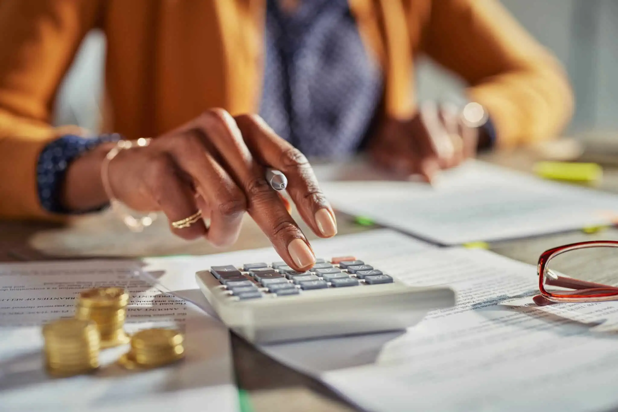 Como são tributados os diferentes tipos de rendimentos? mulher a usar calculadora para calcular o irs com o apoio dos impressos de IRS para imprimir