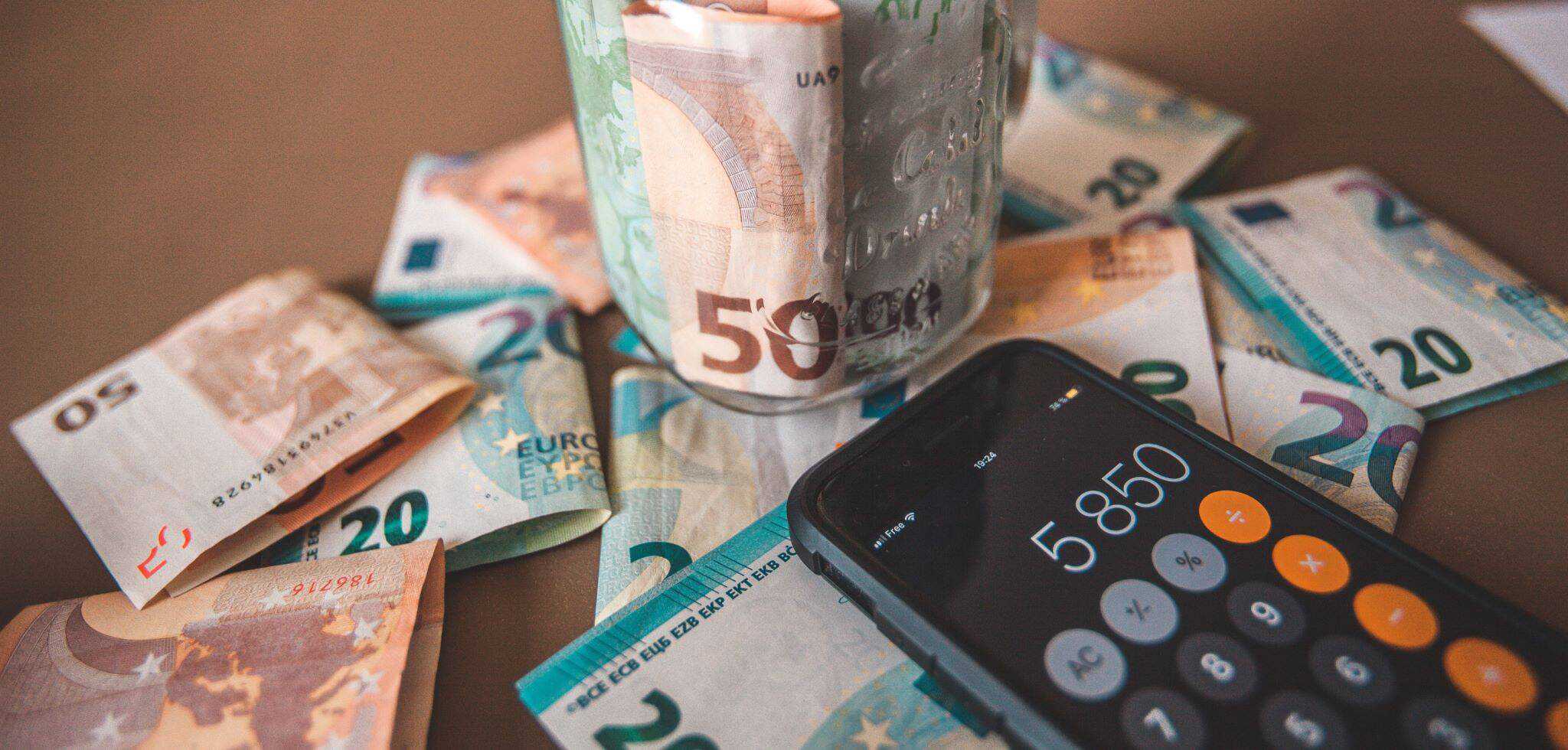 notas de 20 e 50 euros e telemóvel com a calculadora aberta