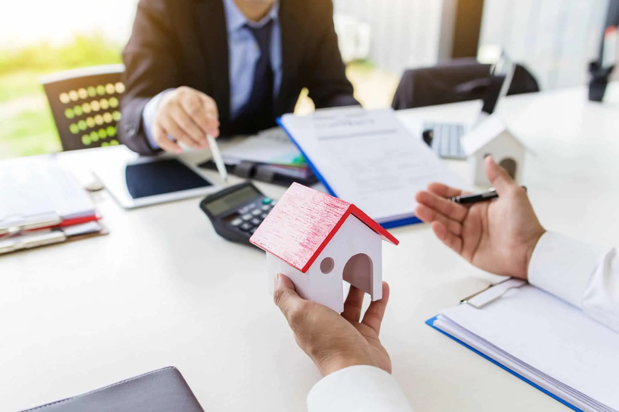 Mais-valias imobiliárias: Em que situações posso ficar isento? duas pessoas sentadas à secretária a fazer contas e a analisar se há direito à isenção das mais-valias imobiliárias