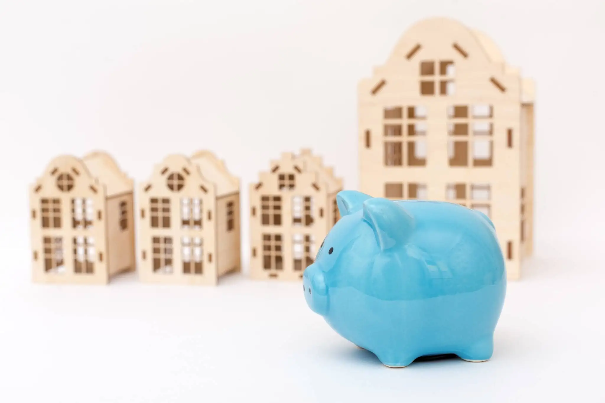 O que são os capitais próprios e quanto preciso de ter para comprar casa? porquinho mealheiro e prédios de madeira a ilustrar que é preciso ter capitais próprios para comprar uma casa
