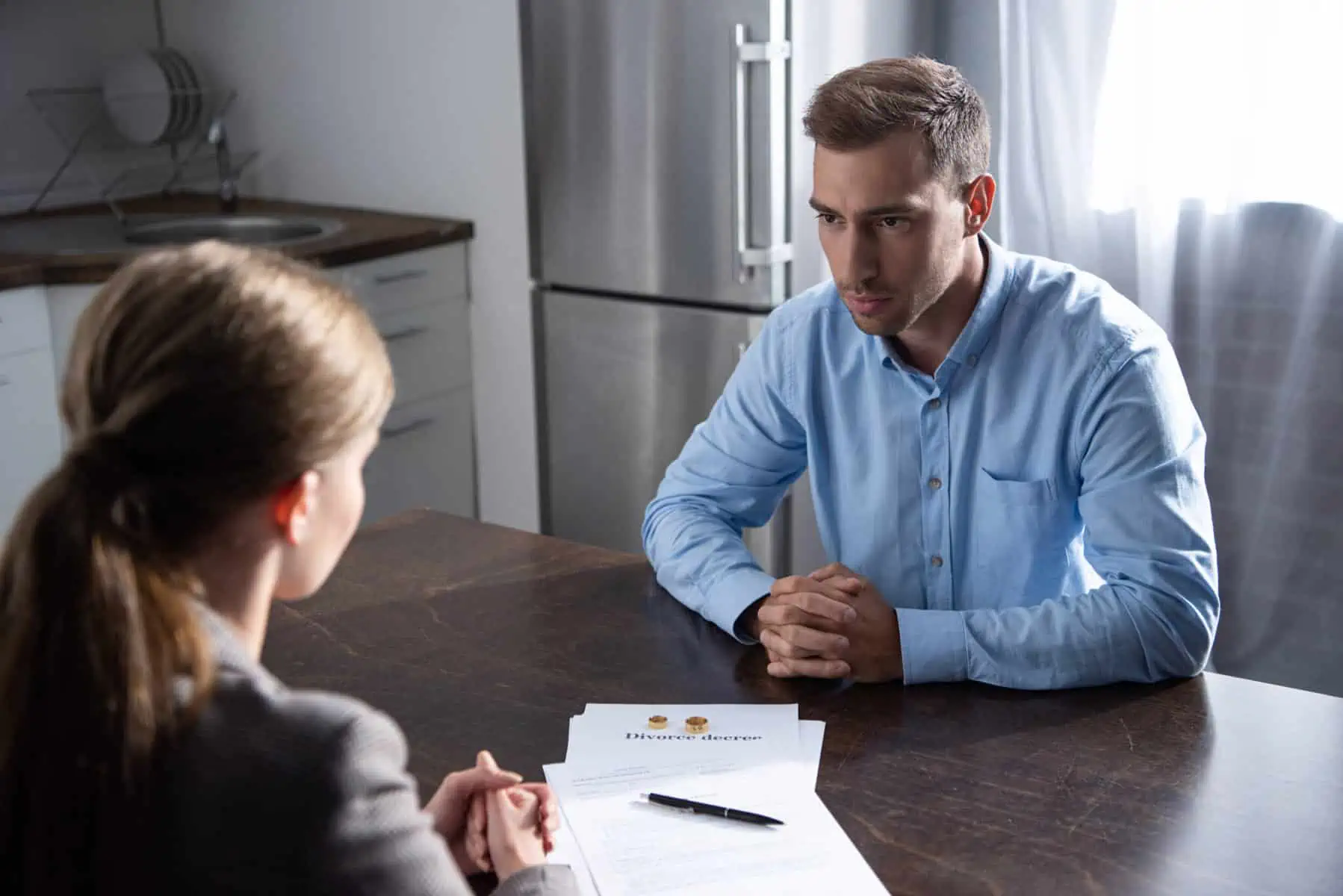 O que é um divórcio amigável e quanto tempo leva a resolver? casal sentado à mesa a oficializar acordos para dar seguimento ao seu divórcio amigável