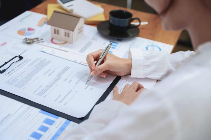 Pessoa após ver uma simulação e aprovação do crédito, assina o contrato com uma caneta