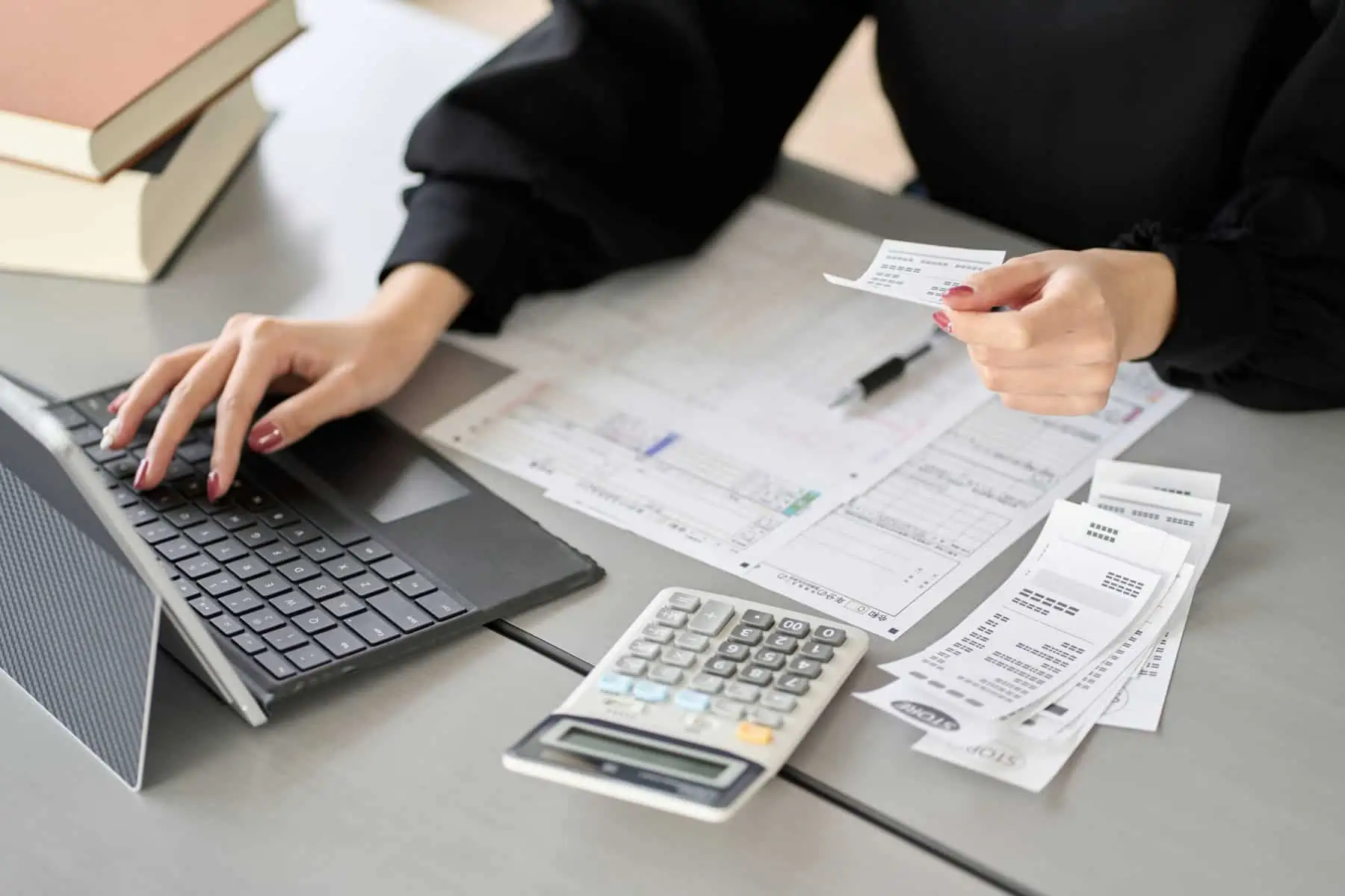 mão de jovem mulher introduz no pc dados retirados das faturas para preparar o IRS automático