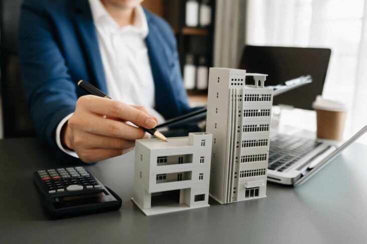 pessoa na secretária com moldes de habitações a ilustrar o leasing imobiliário para habitação