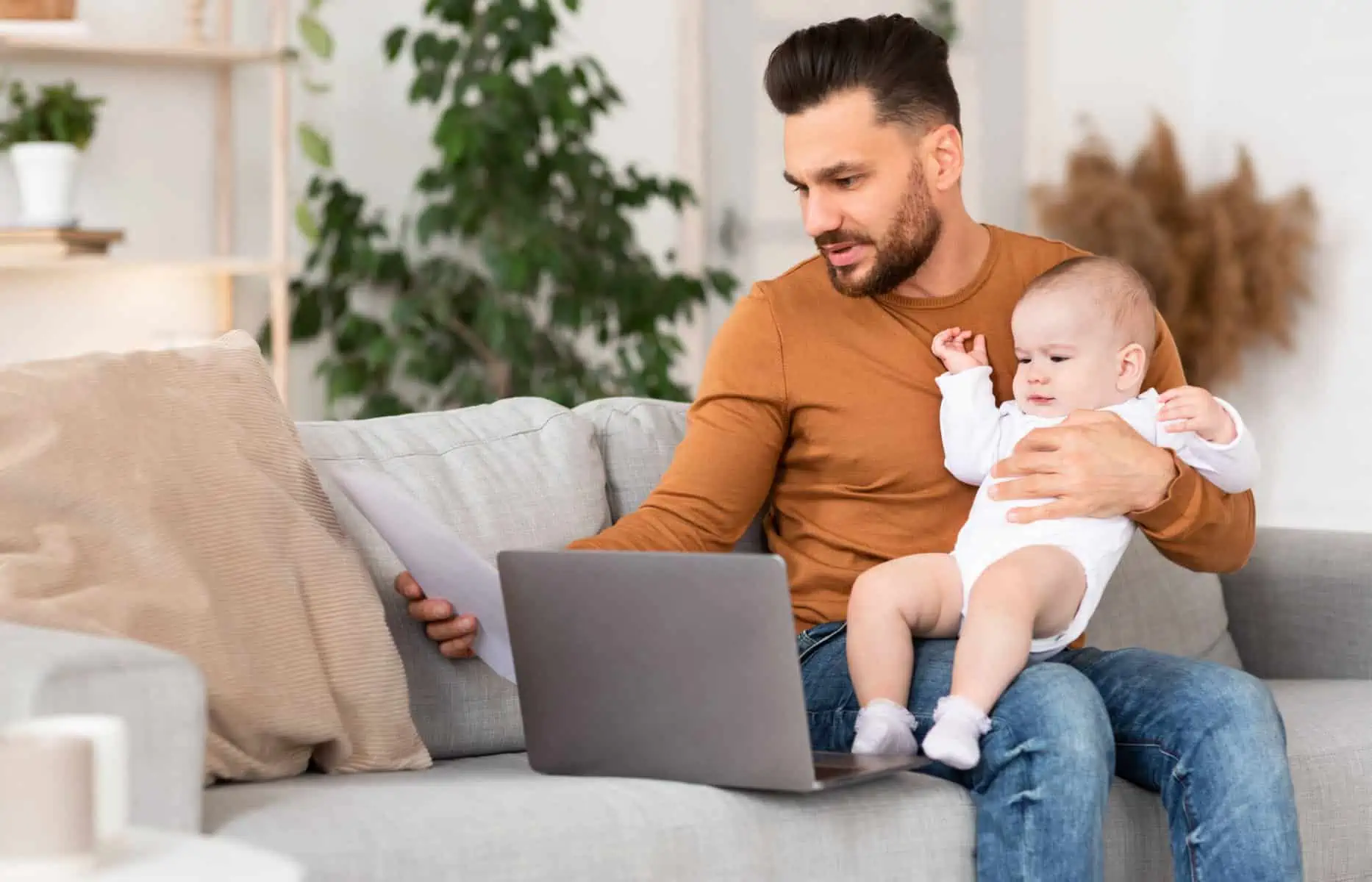 pai com bebé ao colo frente ao computador a certificar-se se as despesas/faturas por dependentes constam no e-fatura