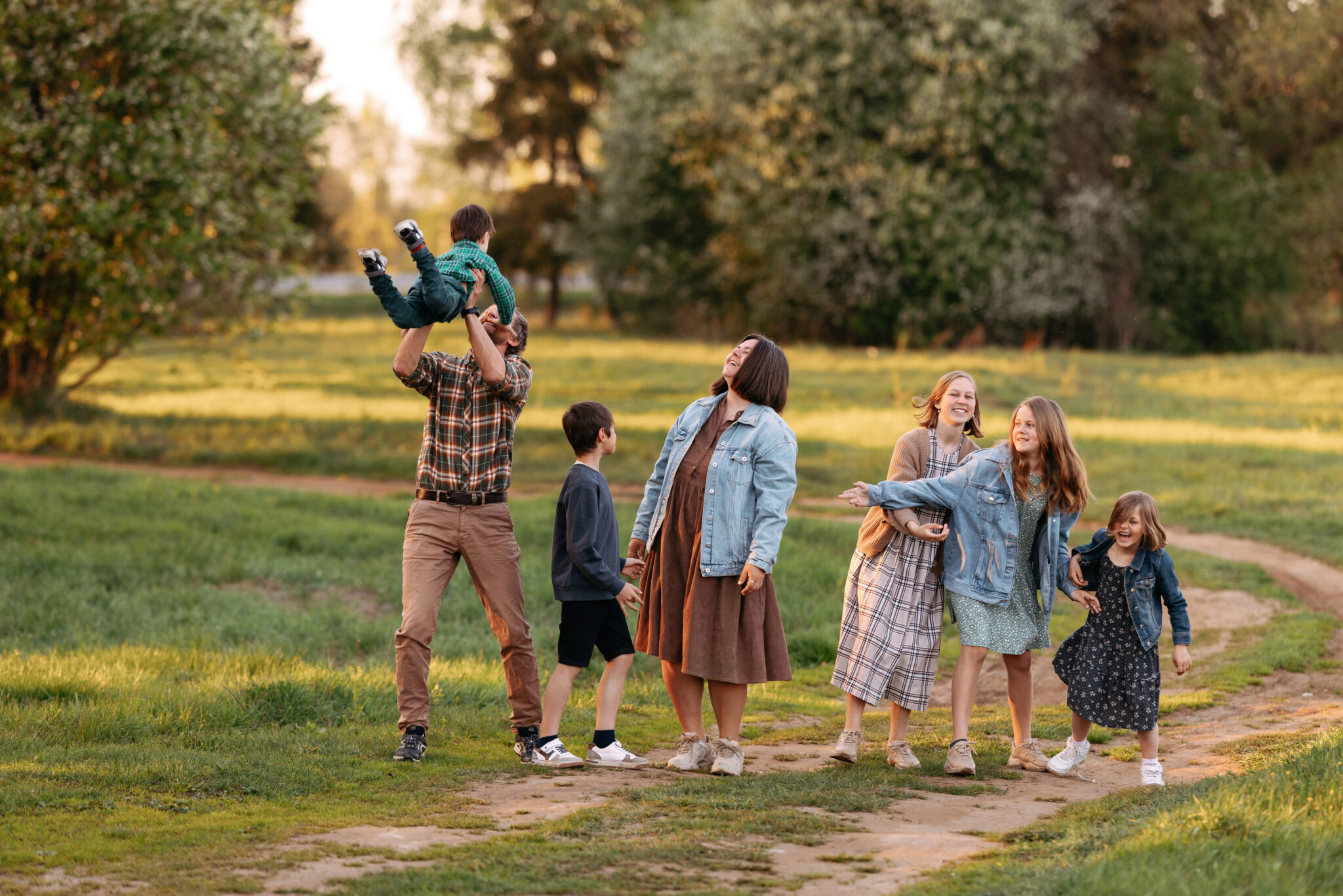 uma família numerosa, mãe e pai com cinco filhos pequenos e pré adolescentes, brincam, felizes, num passeio pela floresta