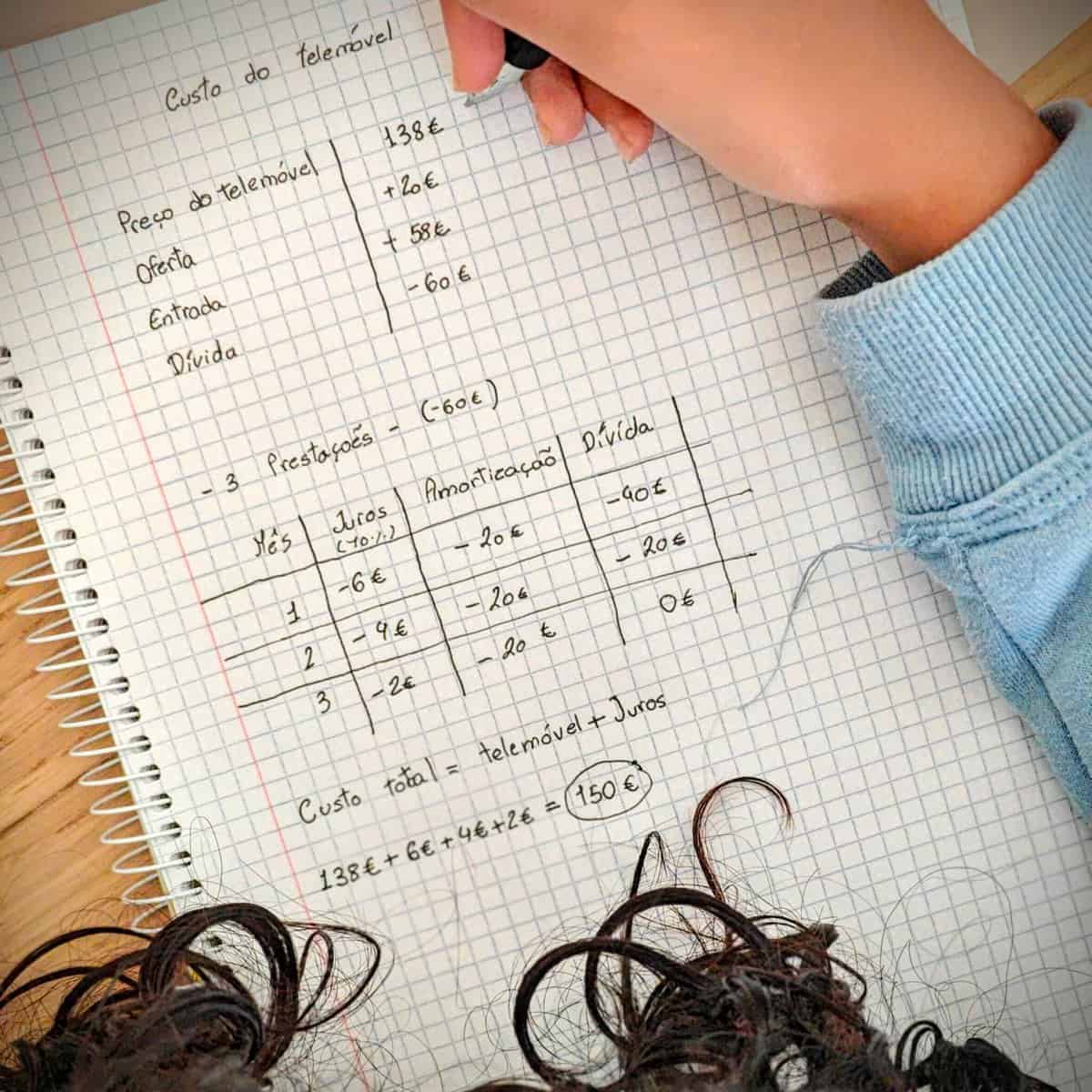 Criança aponta as condições de pagamento de um telemóvel com recurso a crédito.  Numa folha de papel identifica o valor do equipamento, quanto tem de poupanças e qual será o montante de crédito necessário