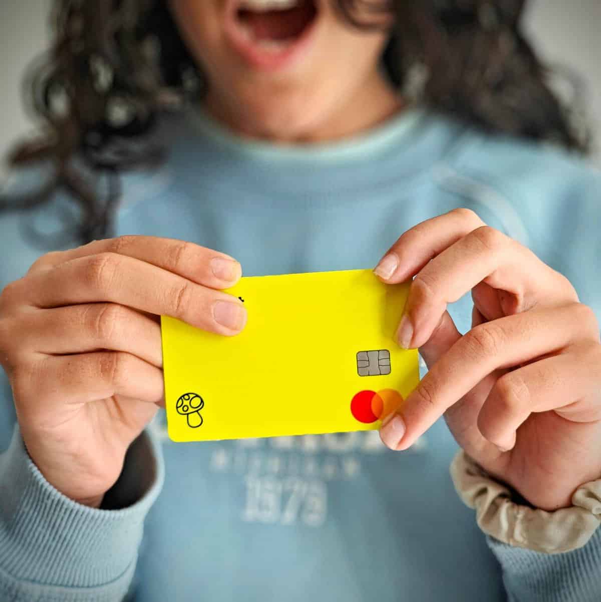 Uma criança segura um cartão multibanco. O seu primeiro cartão aos 12 anos