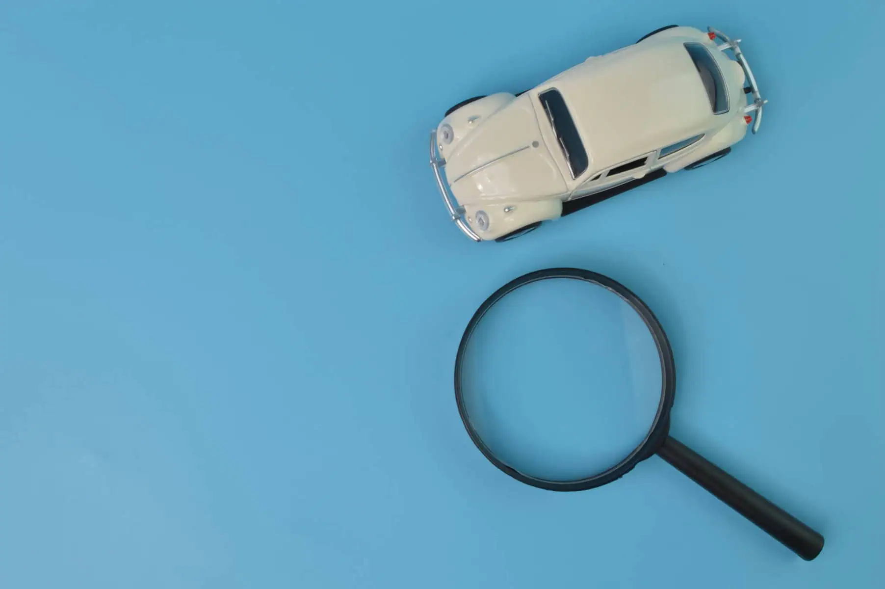 imagem com fundo azul com uma lupa e um carro a ilustrar 8 dicas para reduzir os encargos mensais com o seu automóvel