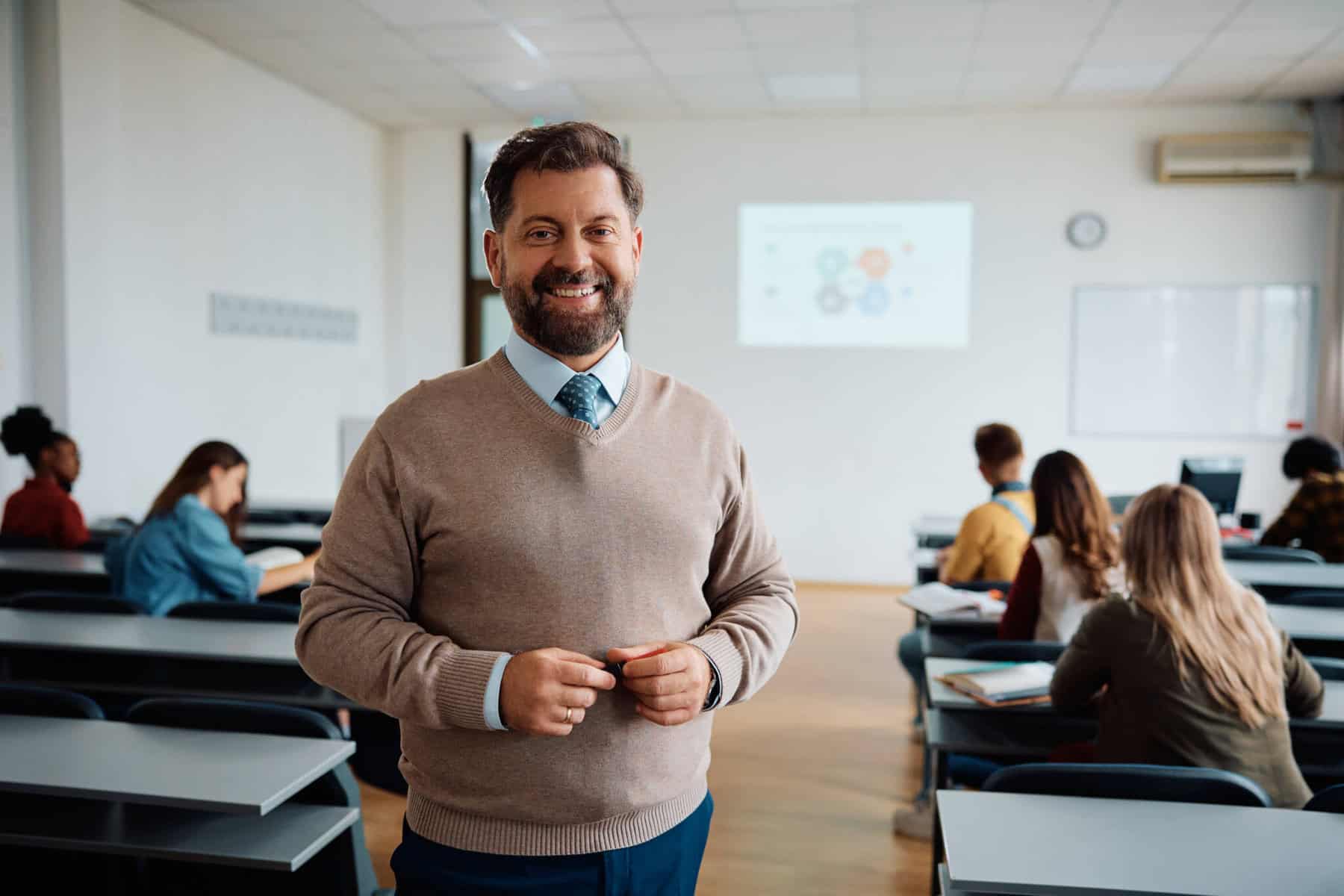 Como pedir o apoio à renda para professores deslocados? professor numa sala de aulas com os alunos a fazer exercícios a ilustrar o apoio à renda para professores deslocados