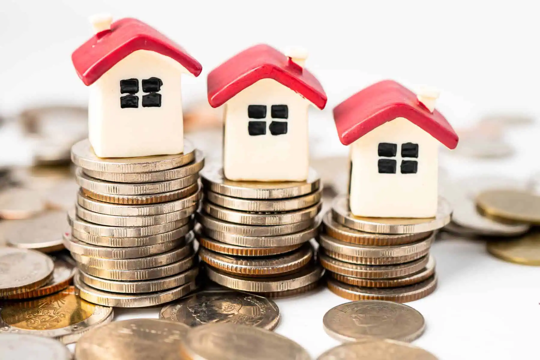 Crédito habitação: Spread no nível mais baixo em 14 anos imagem de casas em miniatura em cima de moedas - alusão aos dados do BdP sobre crédito habitação - sobre o spread abaixo de 1%