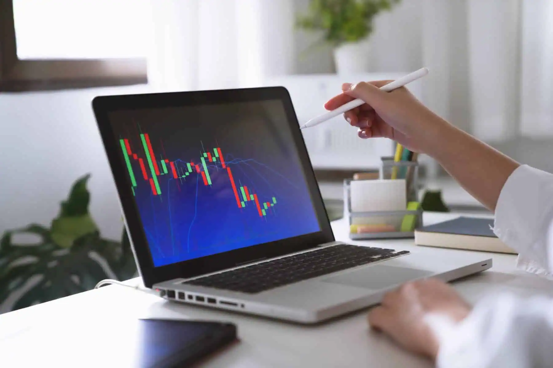 O que são investimentos financeiros e quais as regras para investir? Mãos de mulher a apontar para um computador. No ecrã é possível ver um gráfico com o desempenho de um investimento realizado