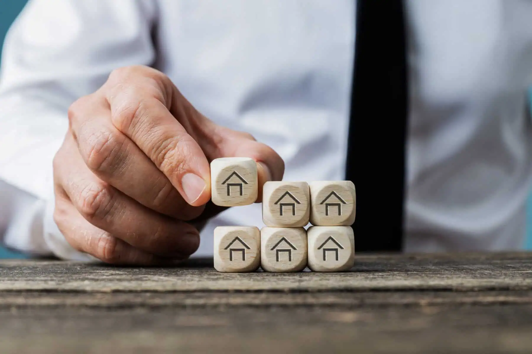 Como funcionam os fundos de investimento imobiliário? homem a empilhar dados com desenho de casas