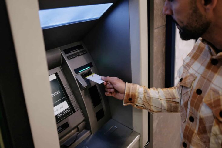 homem a inserir cartão na caixa ATM para ver débitos diretos no multibanco