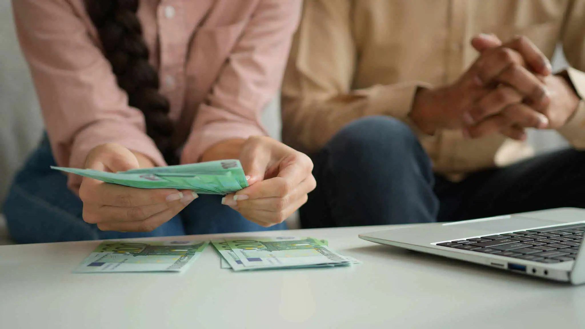 casal a contar dinheiro ao pé do computador. Artigo sobre salário extra no OE