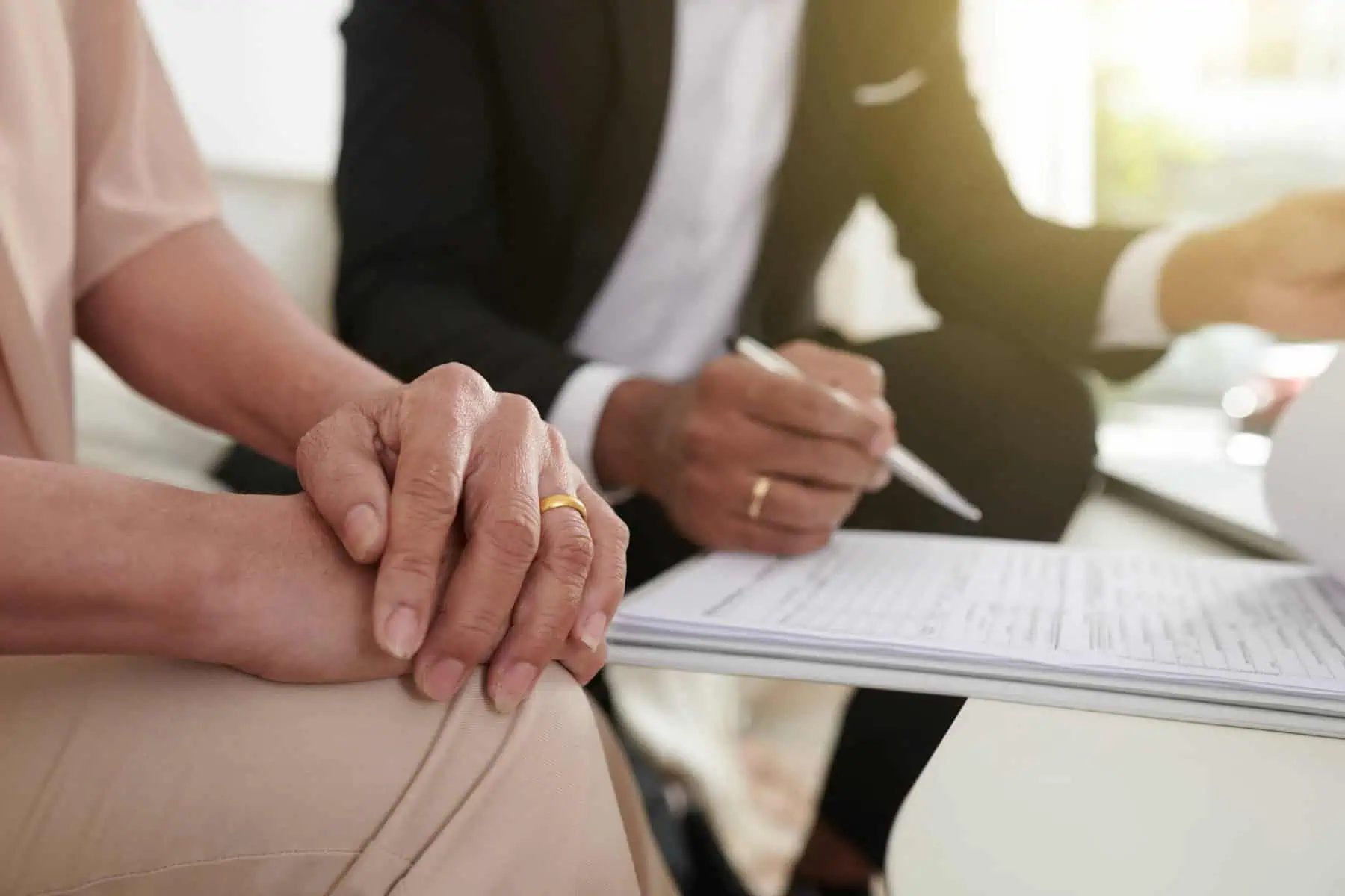 Mãos de um casal a assinar um documento a evocar a contratação de um seguro de vida a 50%.