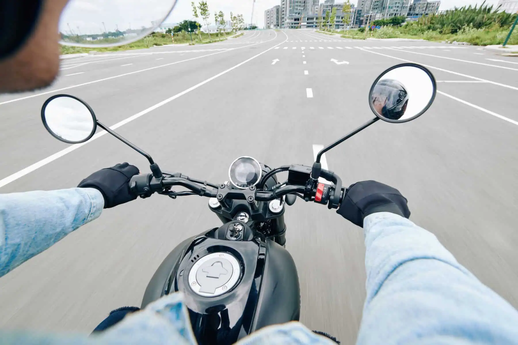 Jovem conduz uma moto numa estrada com várias faixas de rodagem.
