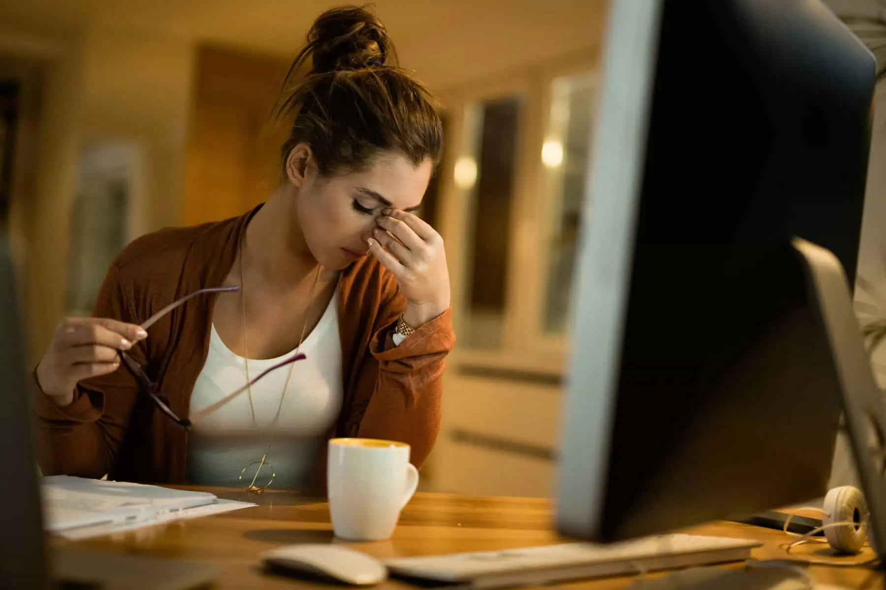 Trabalho Noturno: Impactos, regulamentações e boas práticas Jovem trabalhadora, sentada ao computador, demonstra cansaço, num período em que está a trabalhar em regime de trabalho noturno,