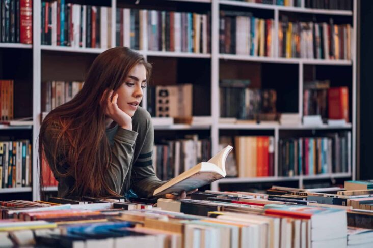 Jovem adulta numa livraria aderente a tentar escolher o livro para usar o seu Cheque-livro