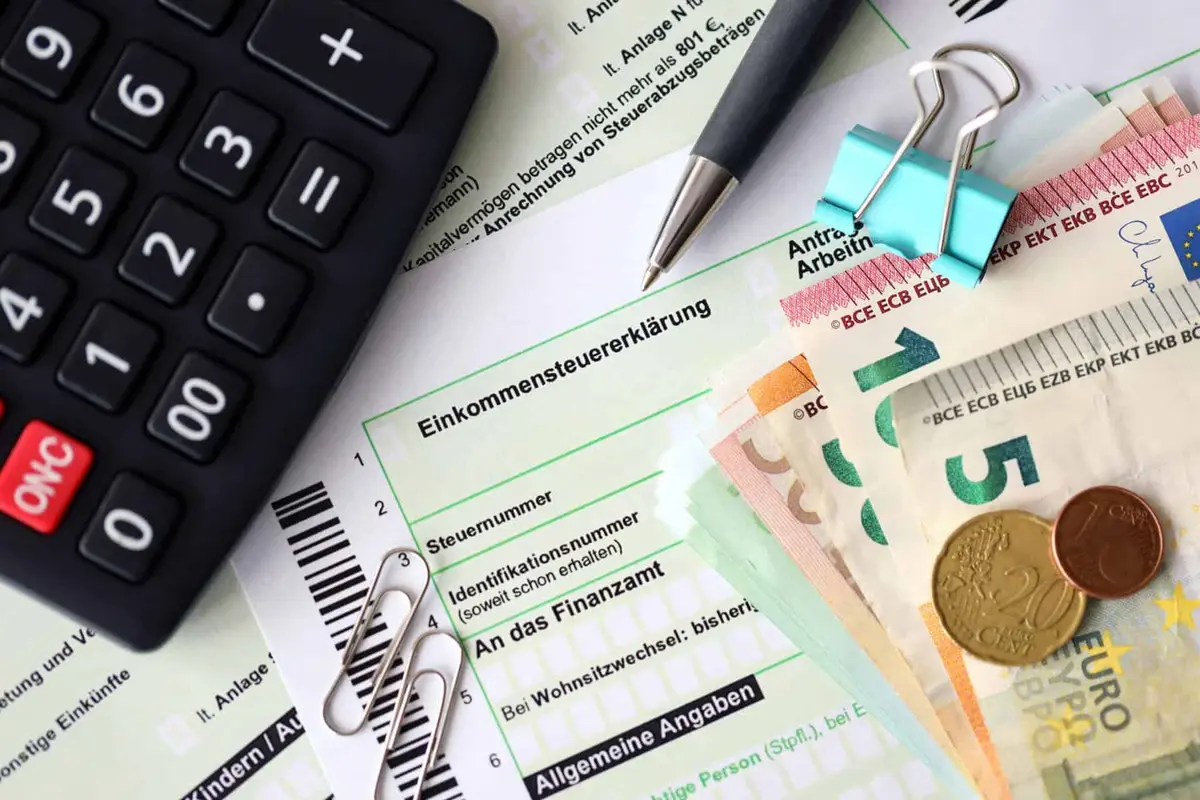 Formulário fiscal com caneta e notas de euro, usado no cálculo do imposto sobre mais-valias