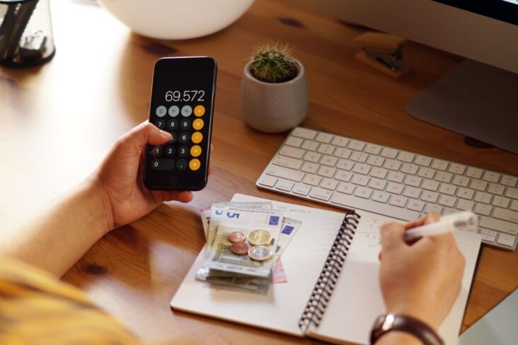 Pessoa com calculadora e caderno na mão faz as contas do orçamento e do que tem de pagar de IRS