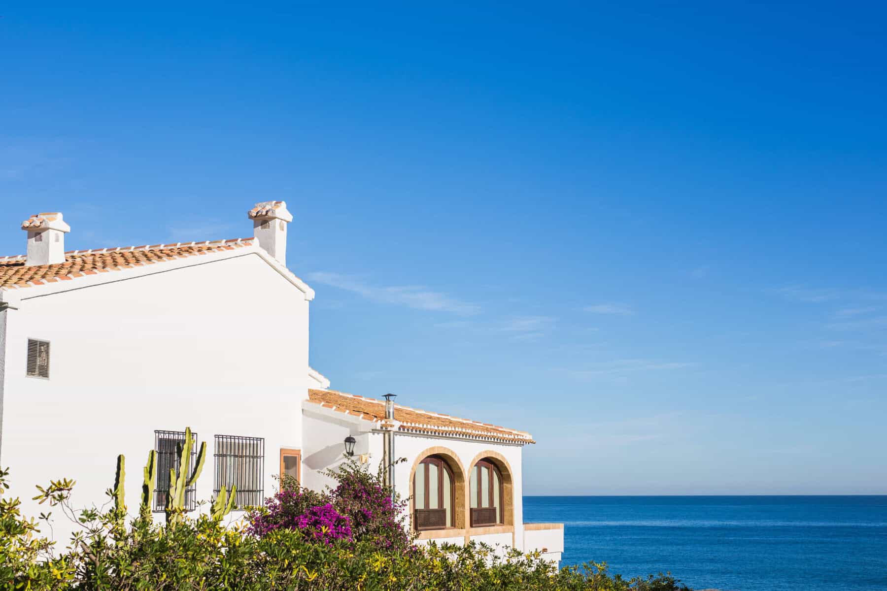 Casa de férias caiada de branco em frente ao mar.