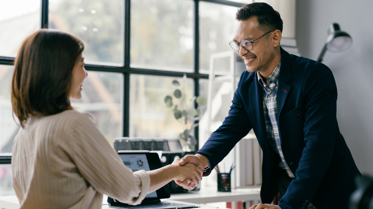 Aperto de mão entre uma entrevistadora e um novo colaborador, após uma entrevista de emprego