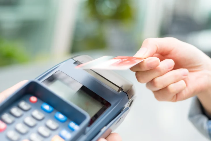 Pessoa paga num terminal multibanco com um cartão de crédito contactless