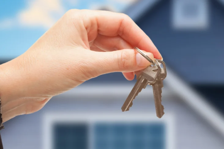 Mulher segura em chaves, com habitação no fundo da fotografia