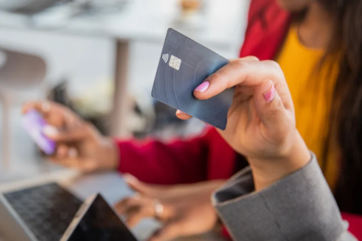 Mulher segura num cartão de crédito enquanto faz compras online