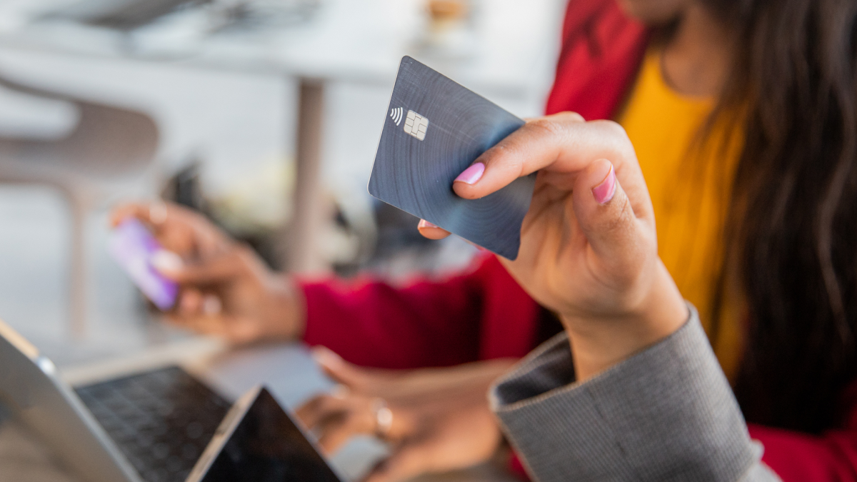 Mulher segura num cartão de crédito enquanto faz compras online