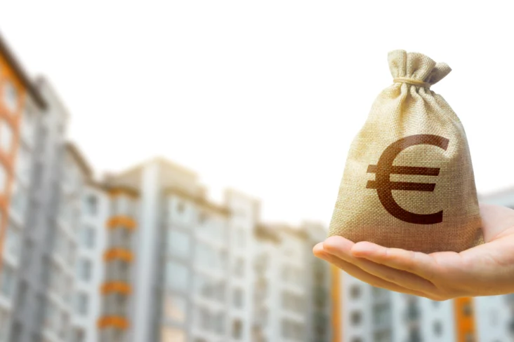 Homem segura numa bolsa de dinheiro à frente de vários prédios residenciais