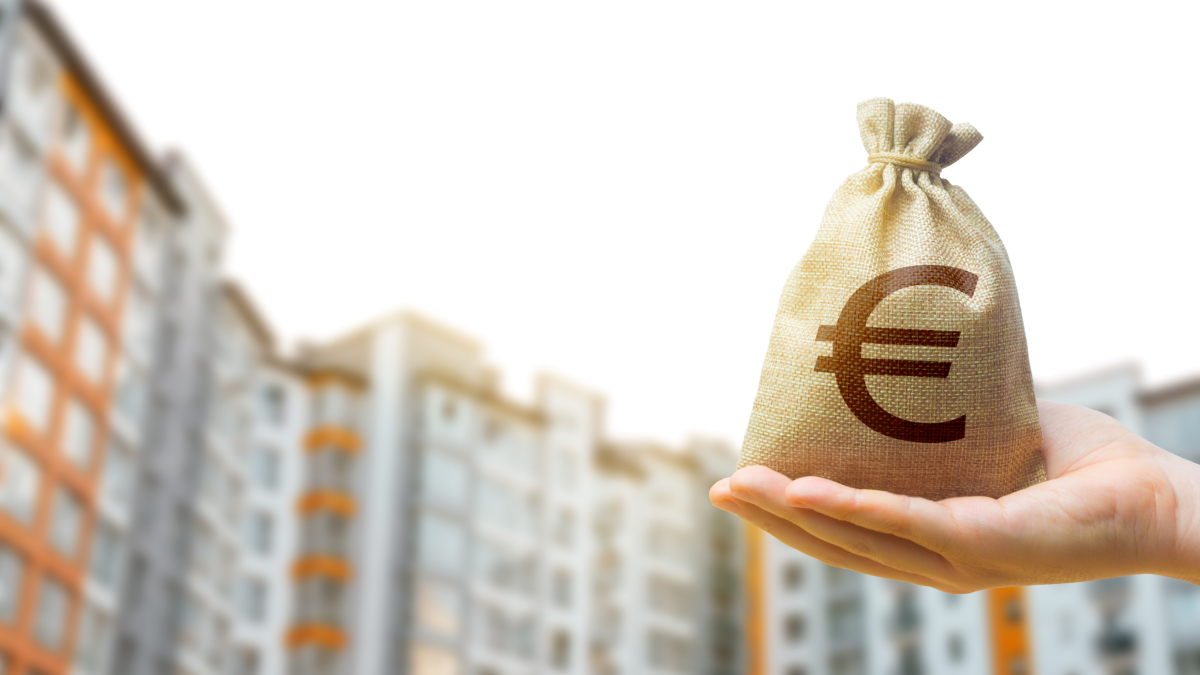 Quase metade dos investidores portugueses só aplica até 10% do rendimento Homem segura numa bolsa de dinheiro à frente de vários prédios residenciais