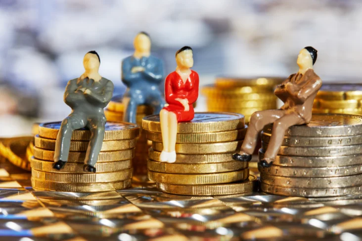 Bonecos sentados sobre moedas empilhadas