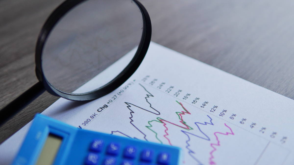 Uma calculadora e lupa sobre uma folha com gráficos