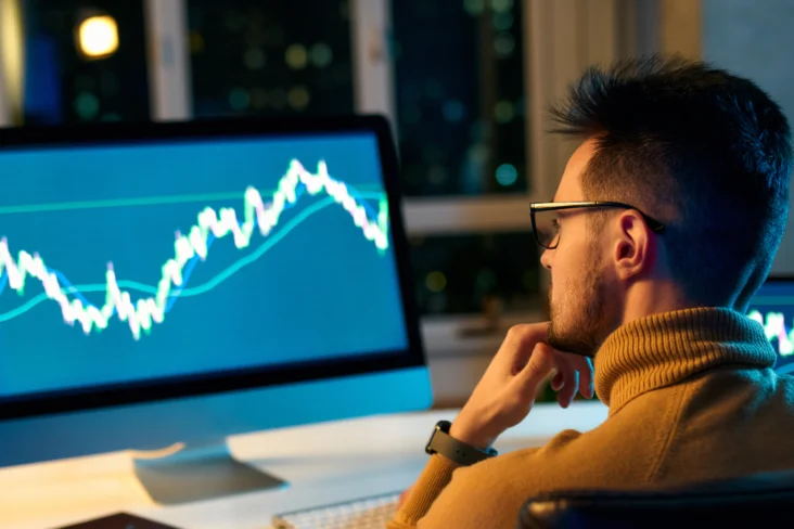 Homem analisa no computador as tendências dos seus investimentos