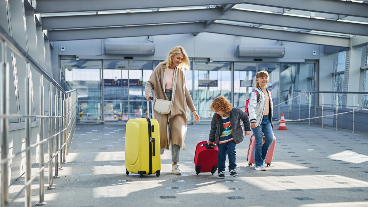 Mãe e filhos carregam malas de viagem pelo aeroporto