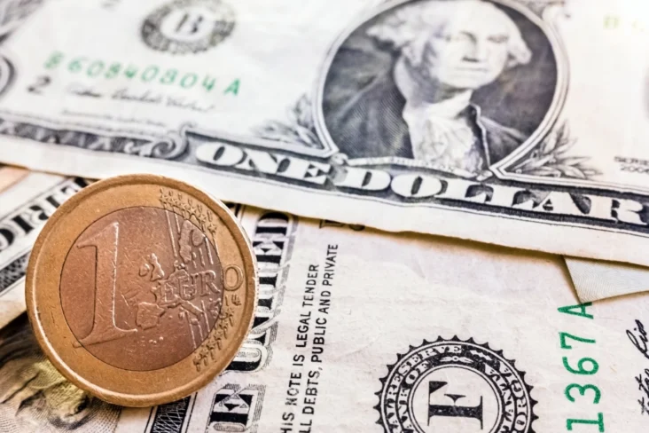 Moeda de um euro sobre várias notas de um dólar