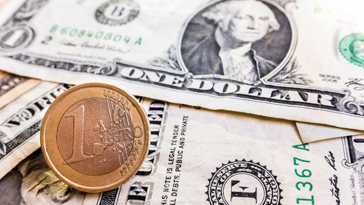 Moeda de um euro sobre várias notas de um dólar