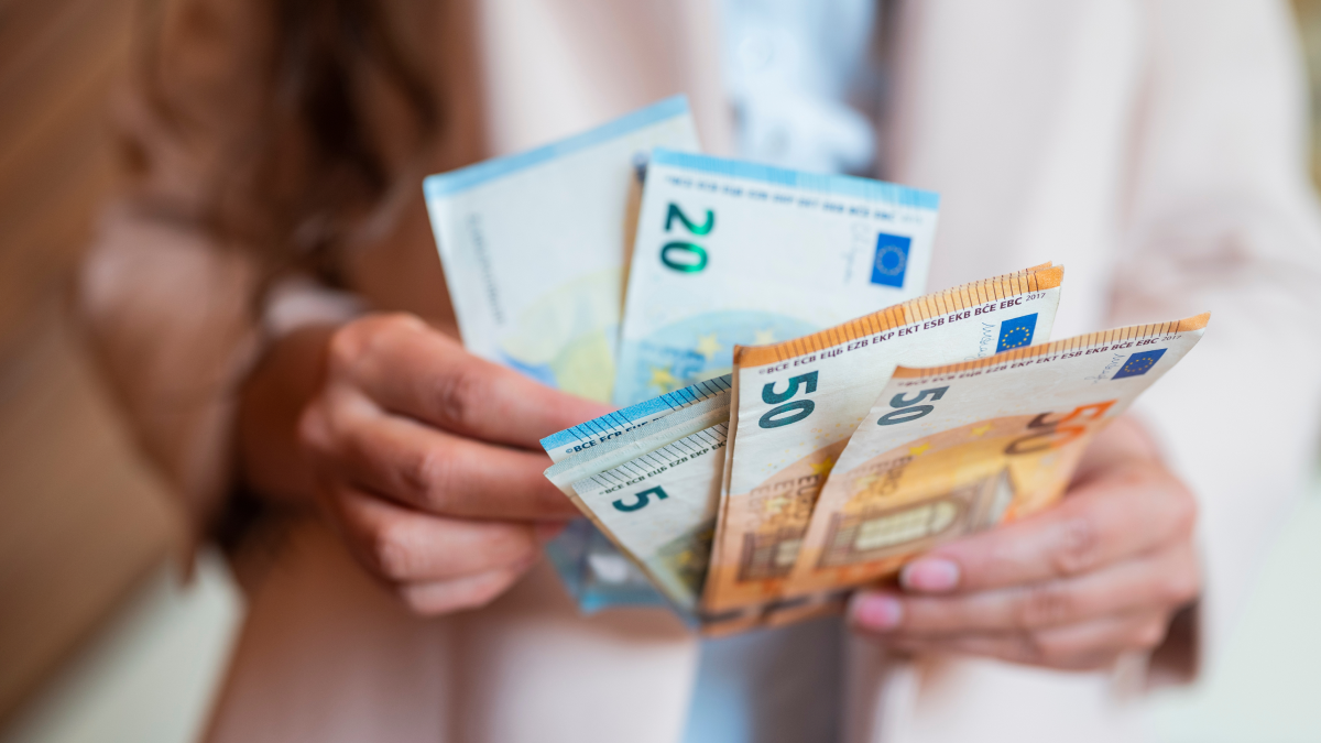 Portugueses investem pouco, têm aversão ao risco e preferem o capital garantido Mulher segura em várias notas de euro