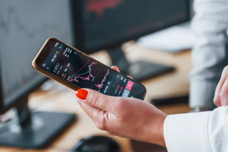 Mulher segura num telemóvel com uma aplicação de investimentos