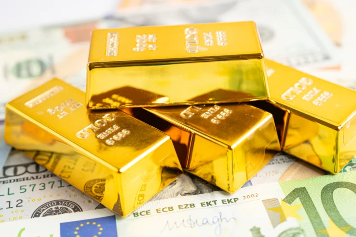 Barras de ouro sobre notas de euro e dólares