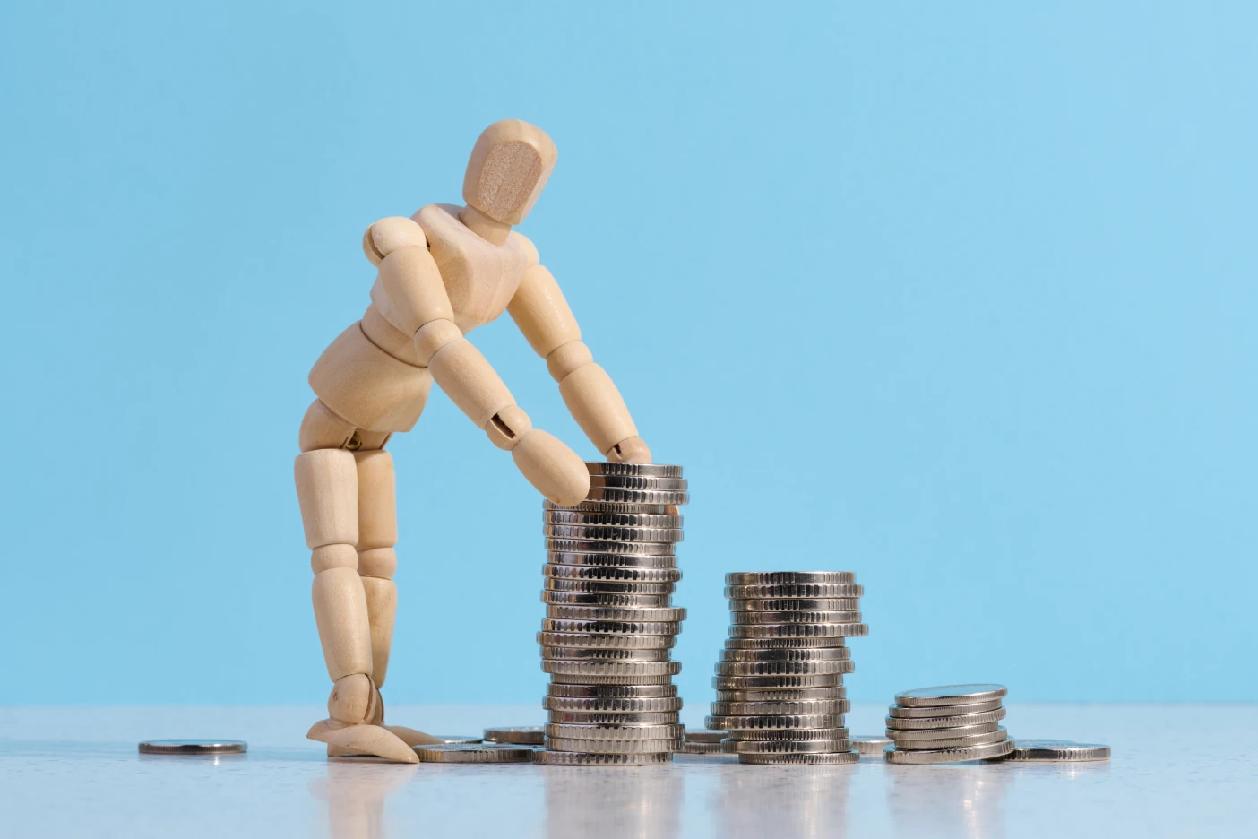 Imagem onde um boneco de madeira constrói uma torre com moedas